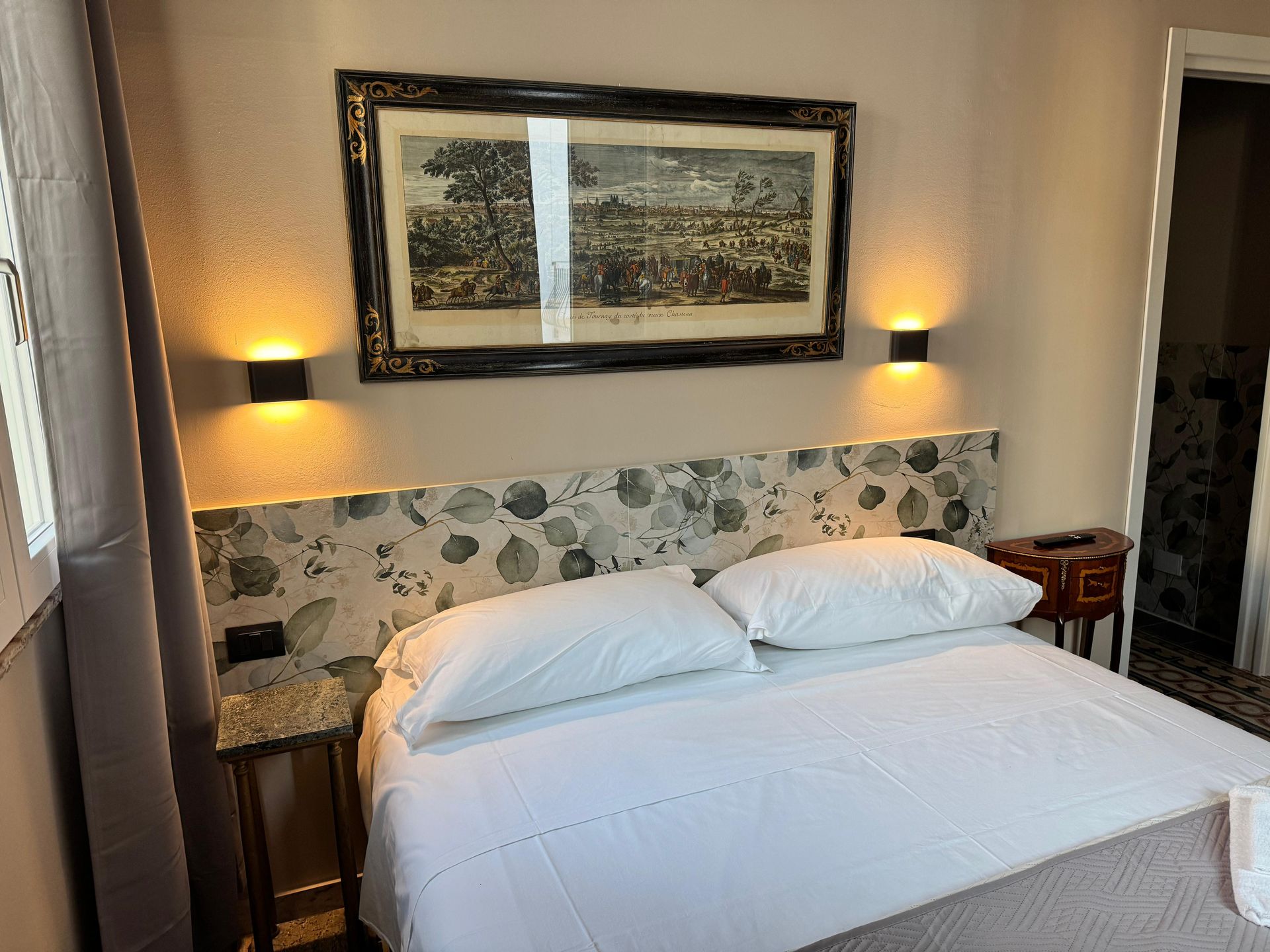 Una camera da letto con un letto, una cassettiera, un comodino, uno specchio e un lampadario.