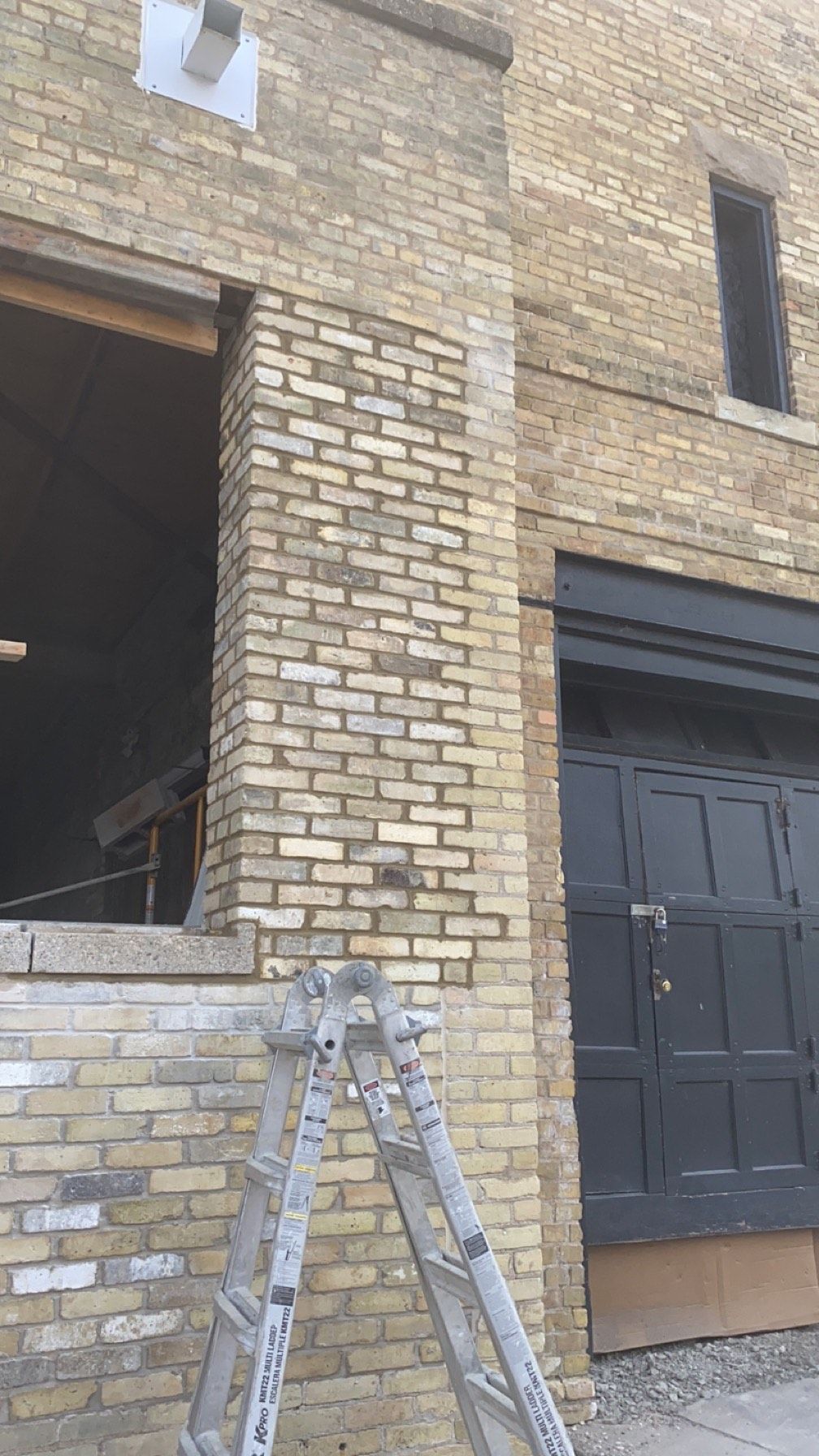 A ladder is sitting in front of a brick building.