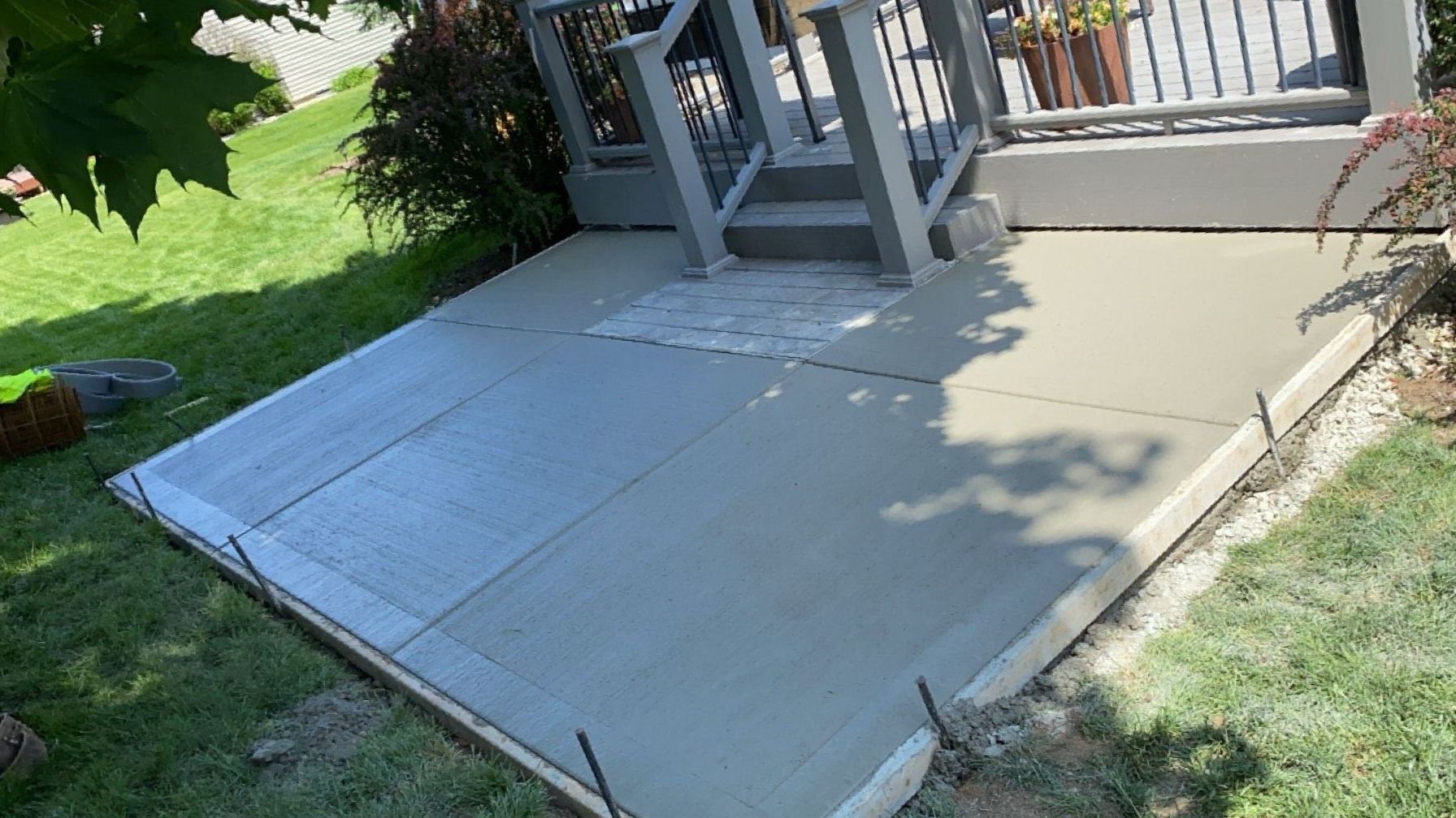 A concrete patio is being built in the backyard of a house.