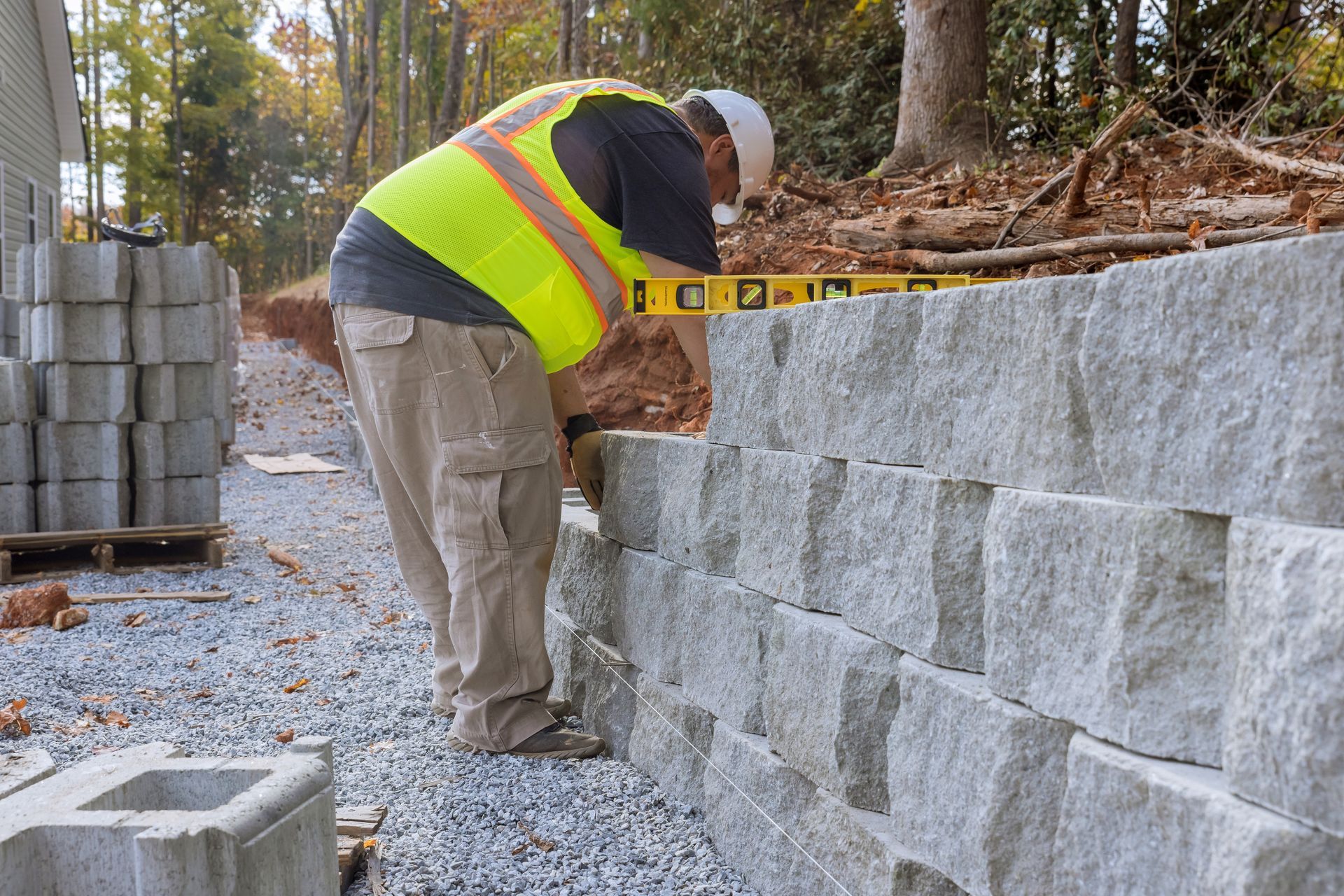 A construction worker is using a level to level a stone wall.