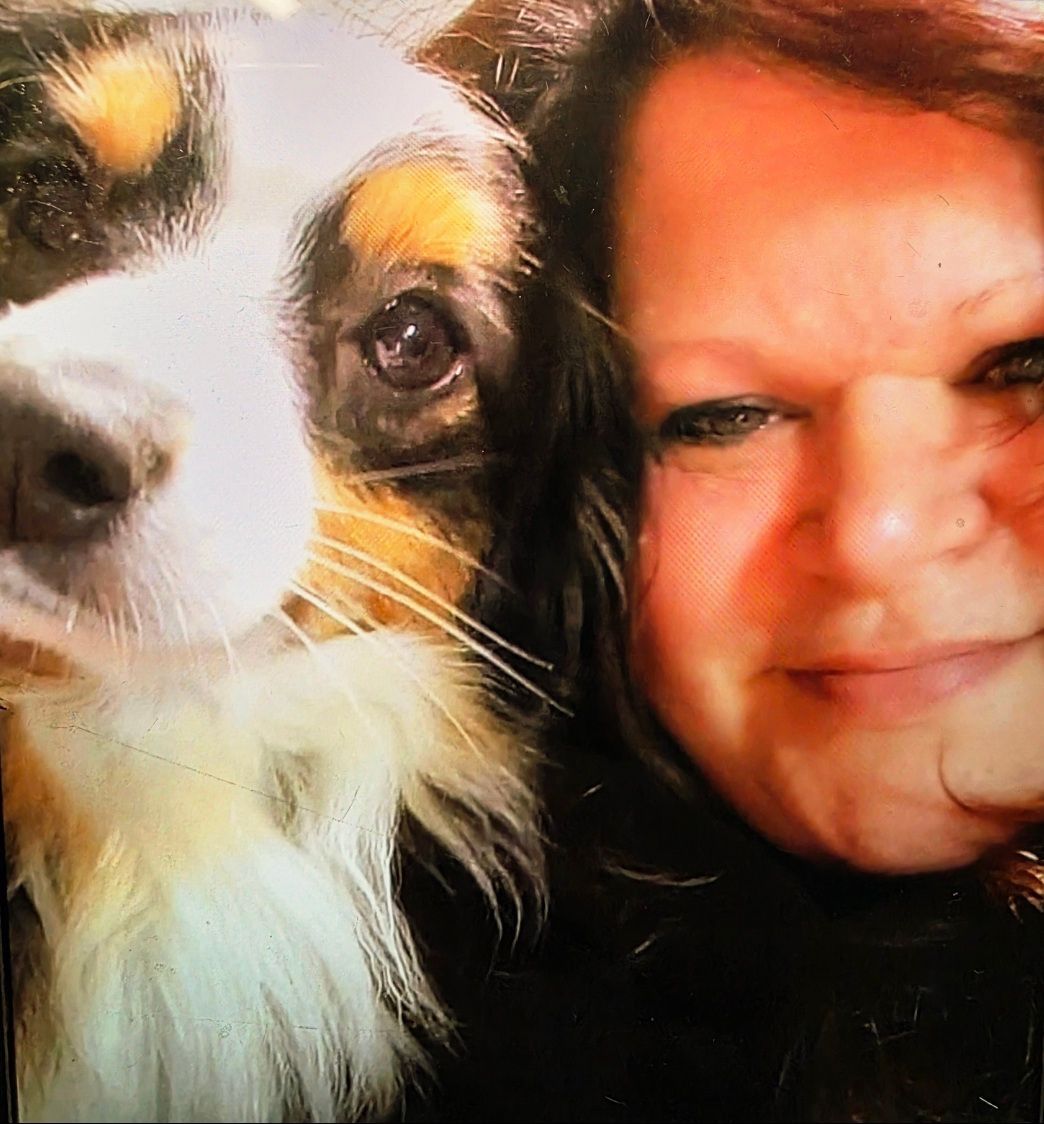 Woman smiling beside a tricolor dog in a close-up selfie