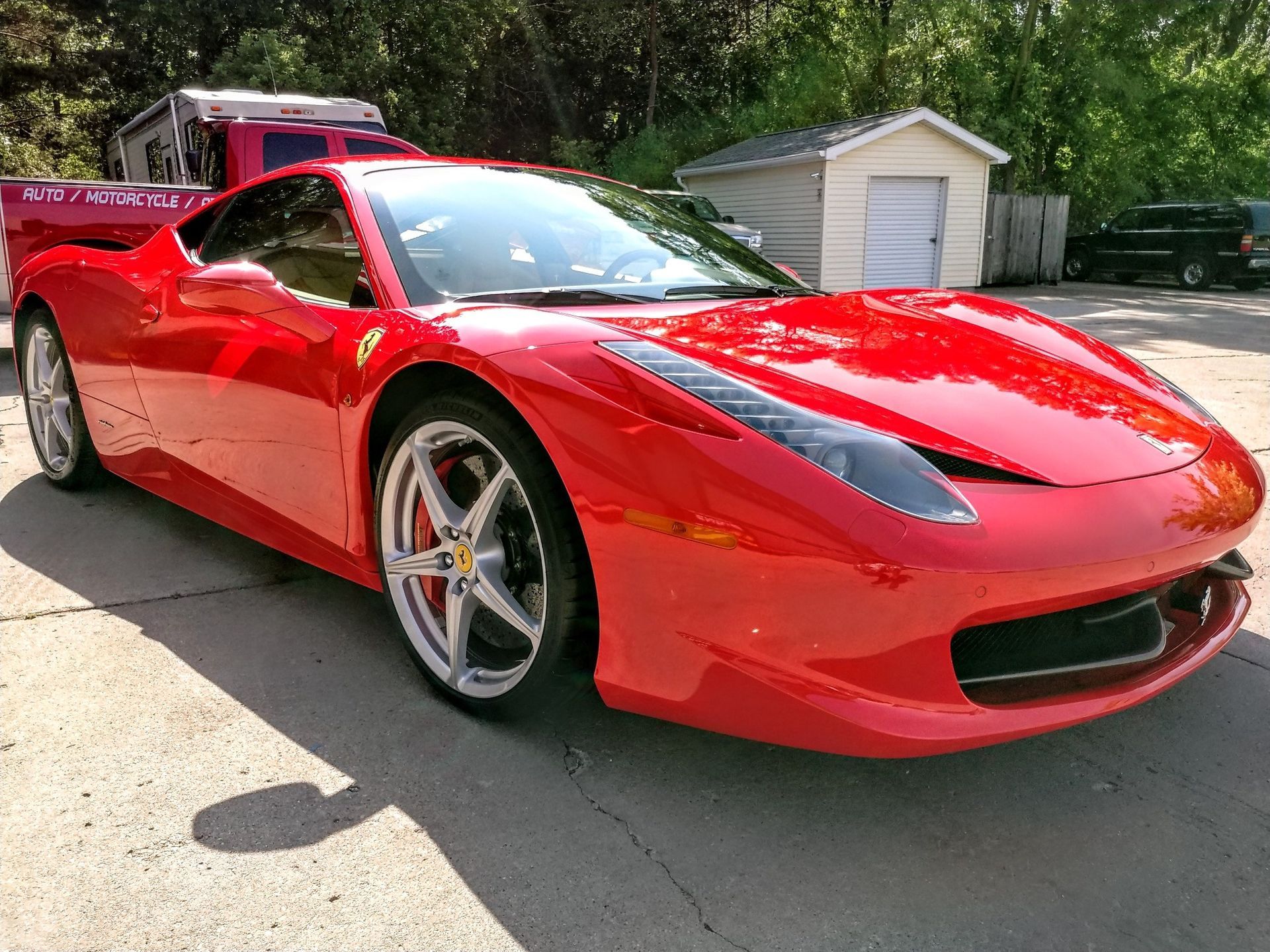 A red sports car is parked in front of a garage.