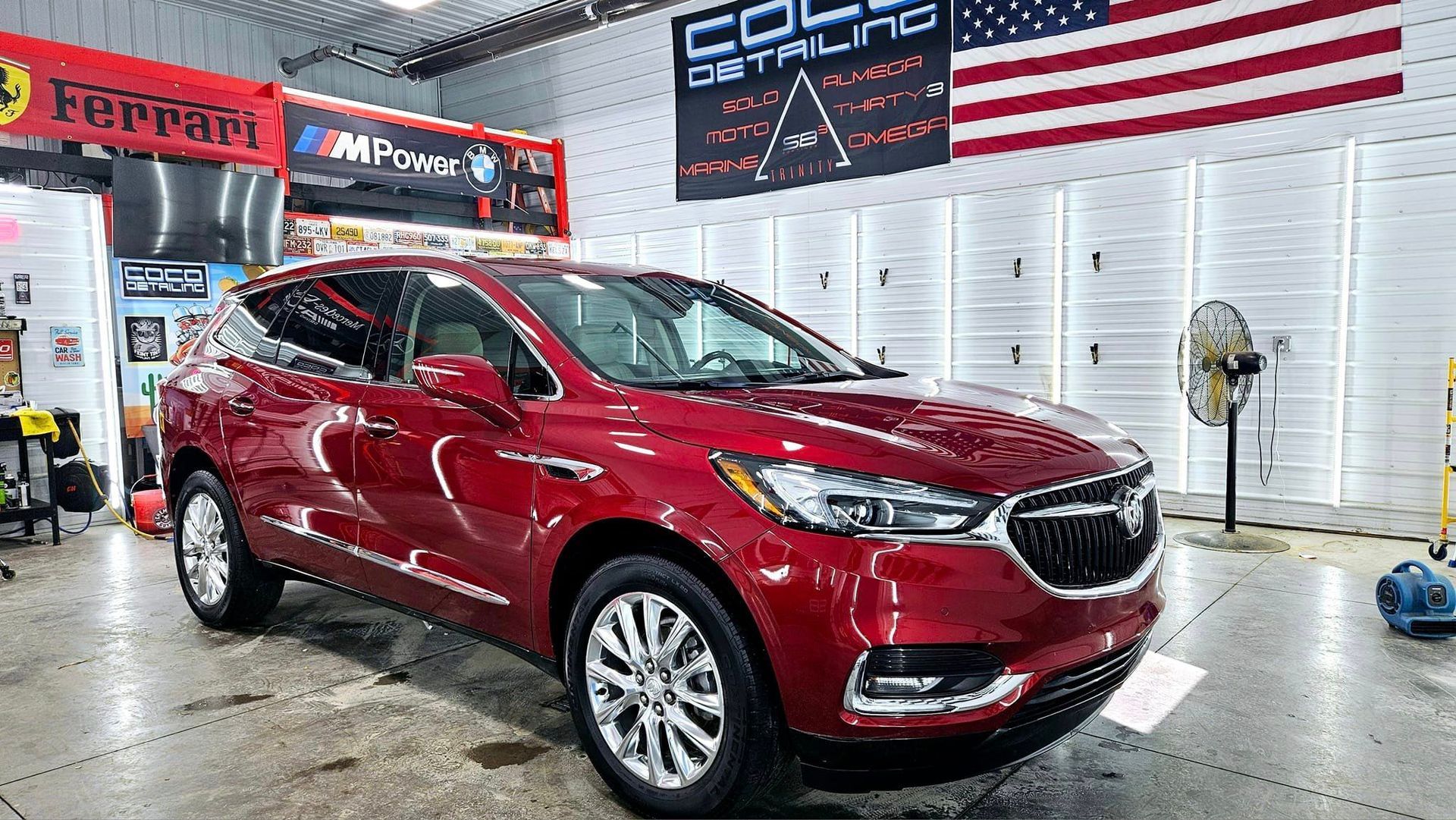 A red buick enclave is sitting in a garage next to an american flag.