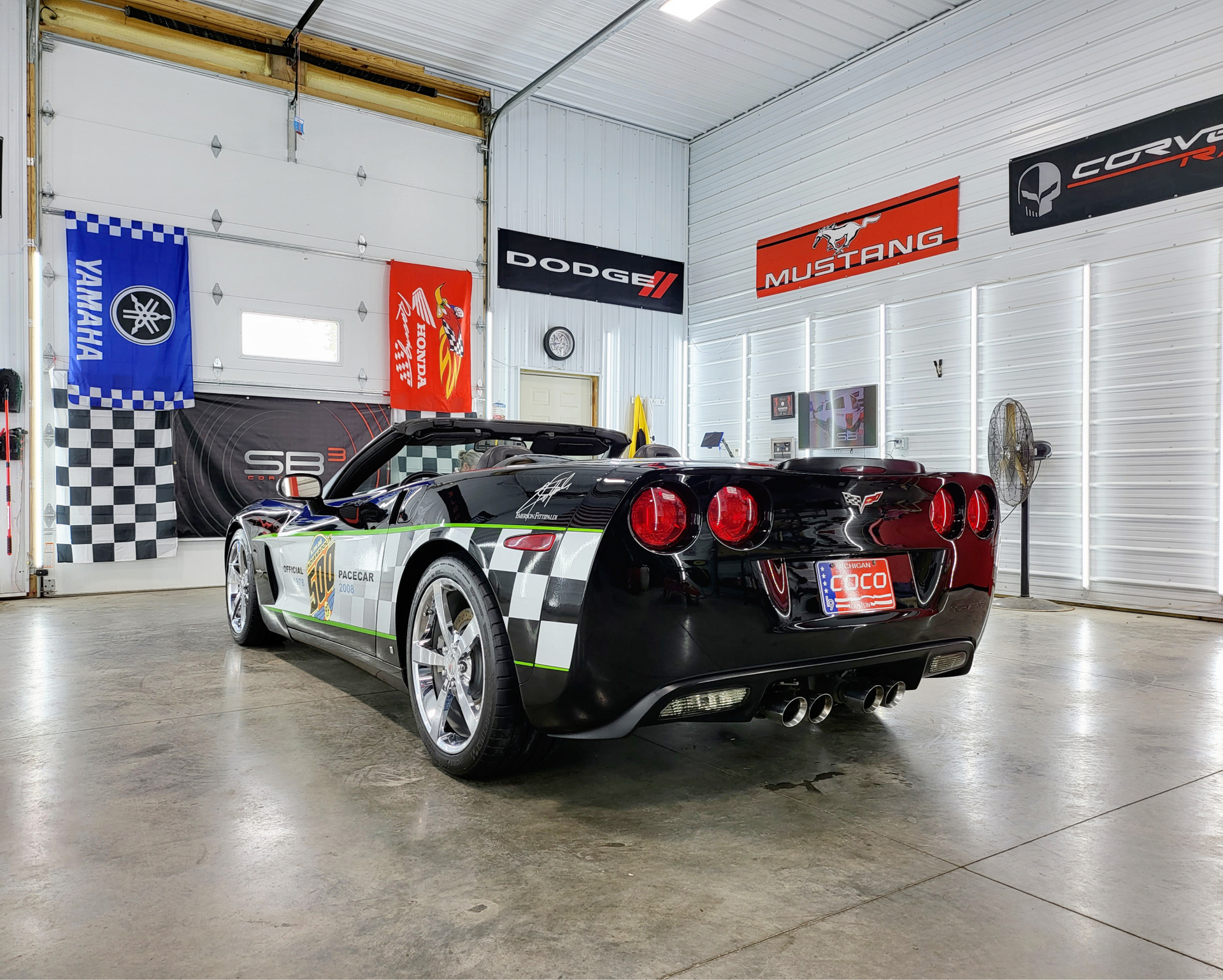 A black corvette convertible is parked in a garage.