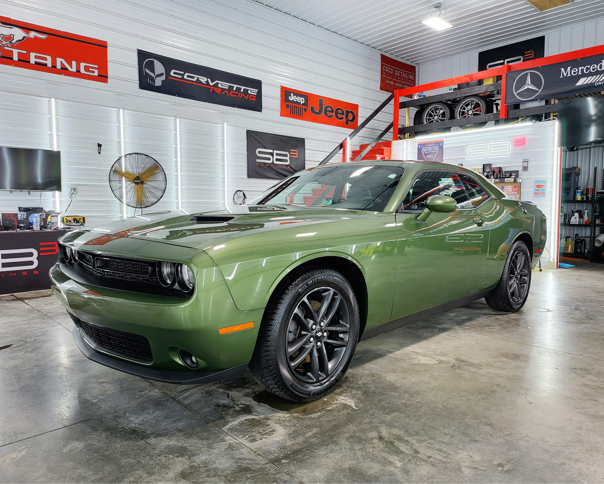 A green dodge challenger is parked in a garage.