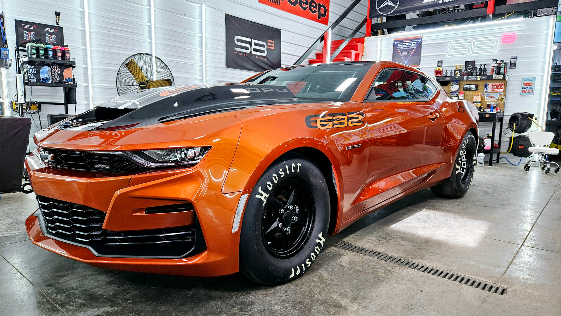 An orange chevrolet camaro is parked in a garage.