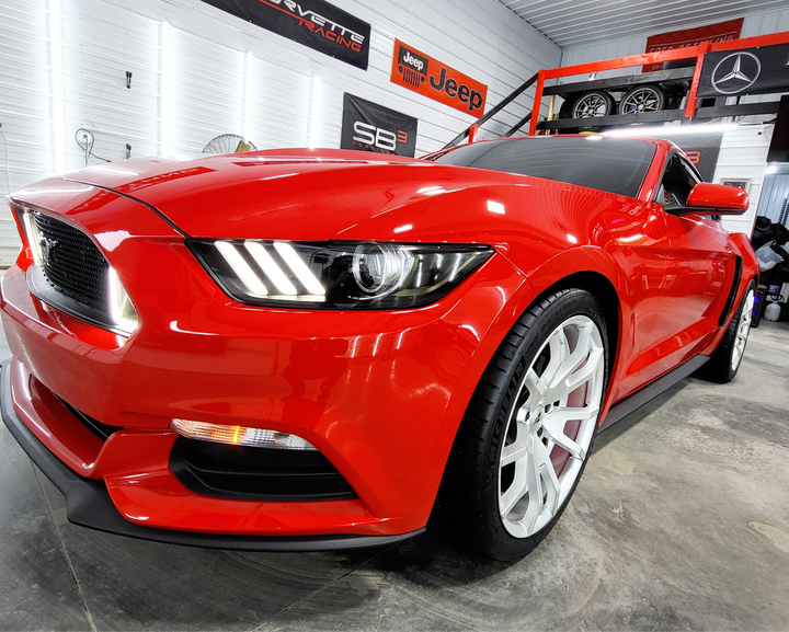 A red ford mustang is parked in a garage.