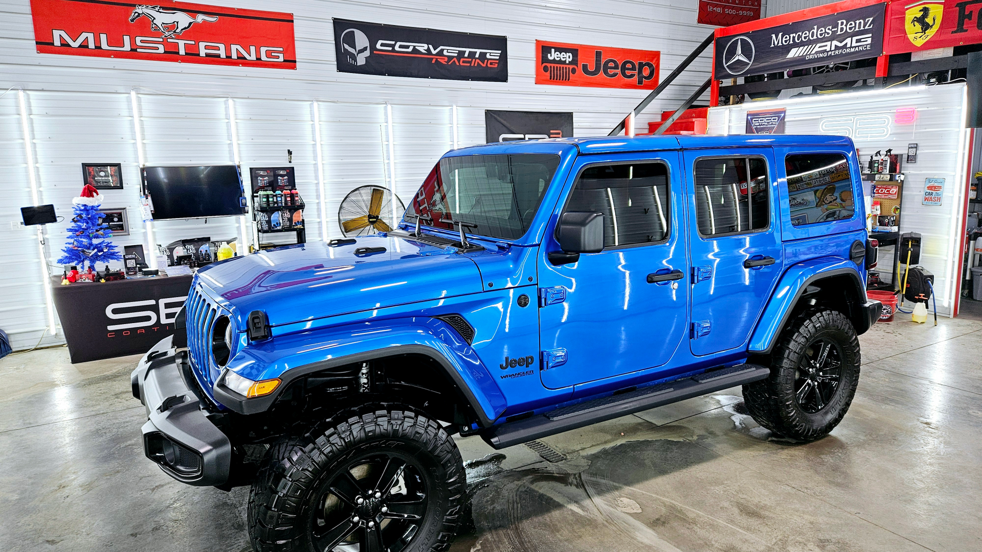 A blue jeep wrangler is parked in a showroom.