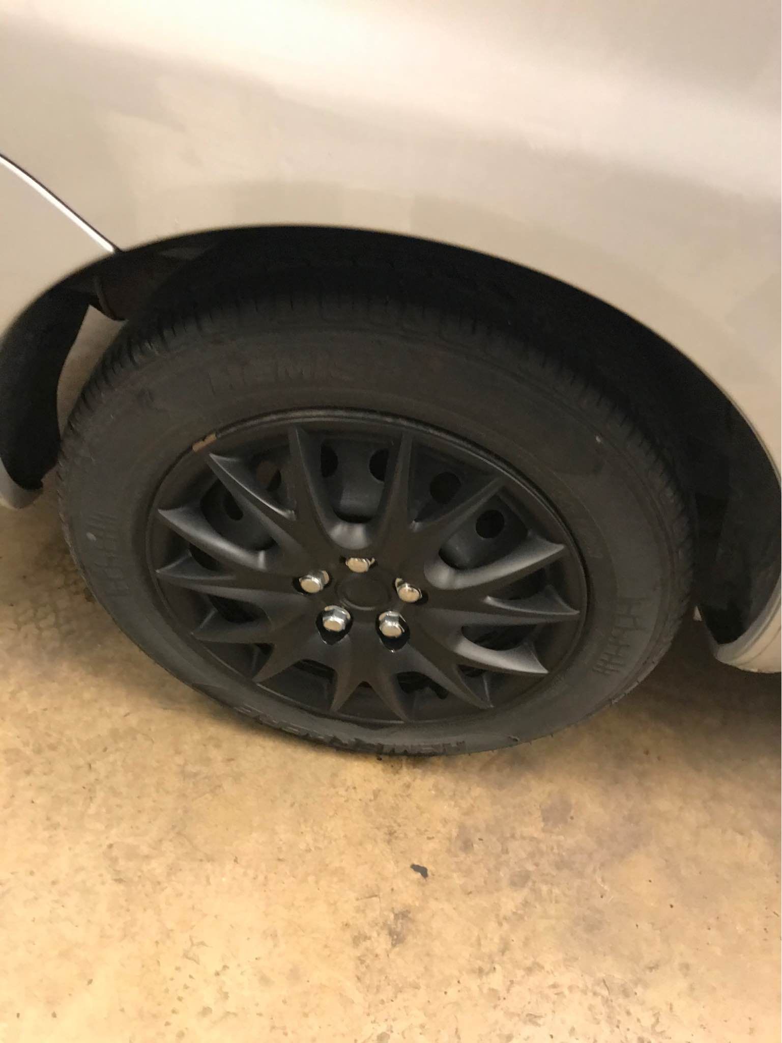 Black car tire with a black hubcap on a silver car.