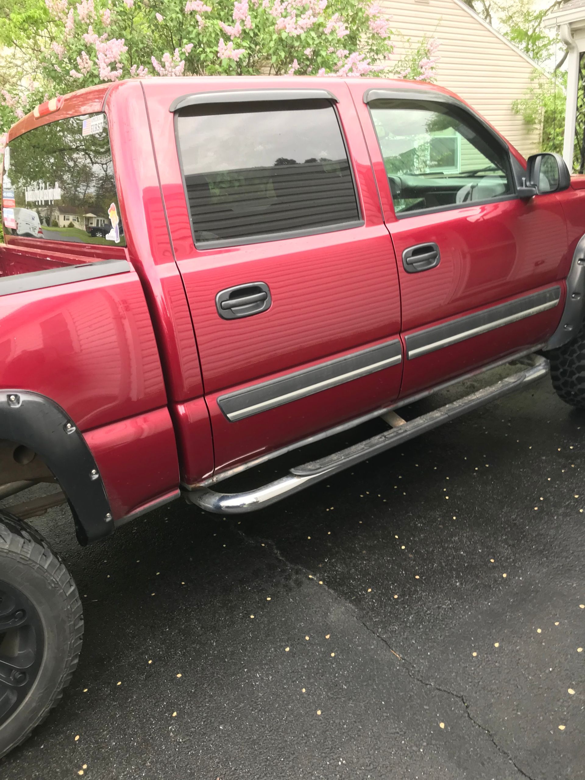 Red pickup truck with running boards and black fender flares parked on asphalt.