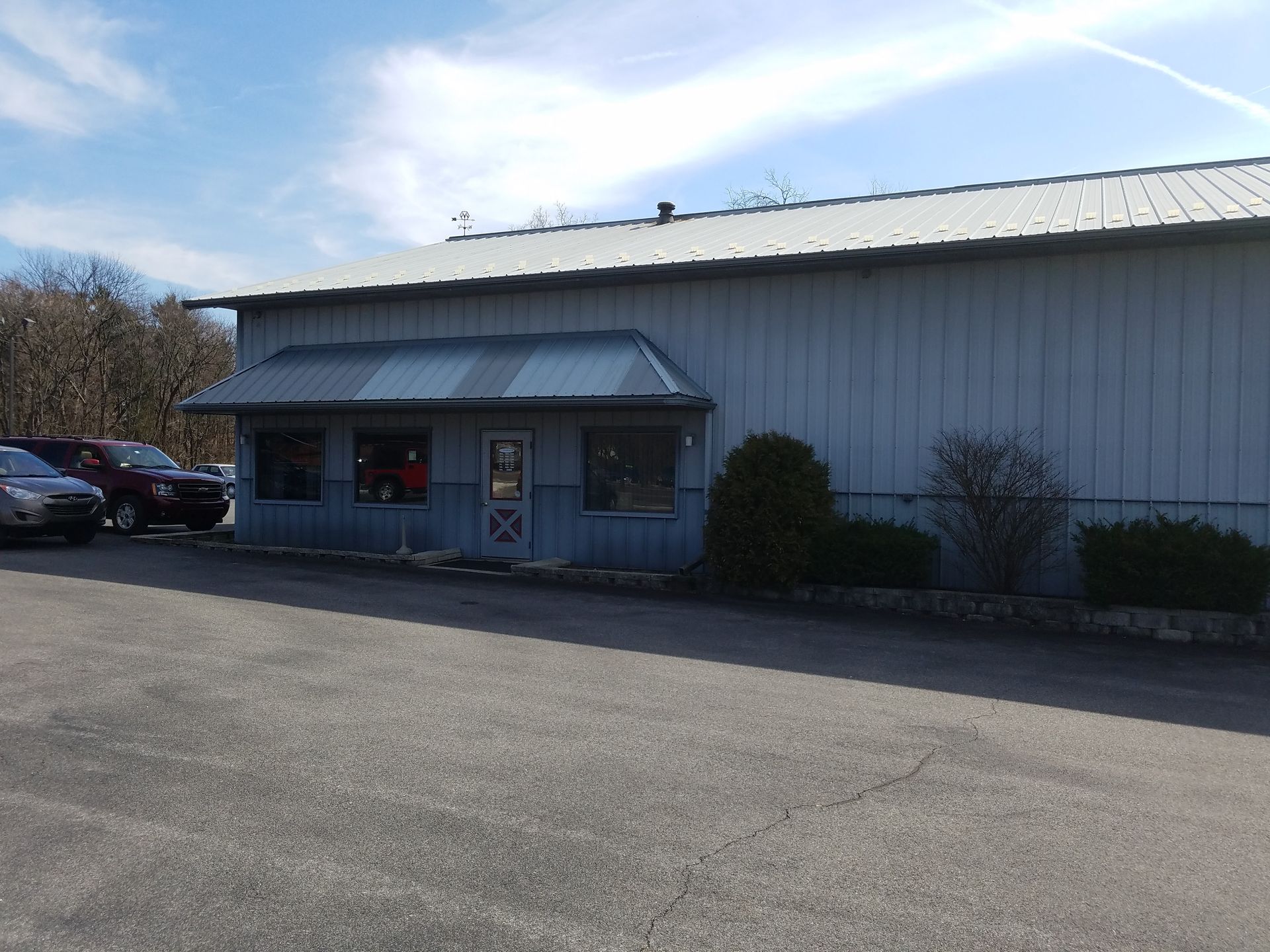 Blue building with awning, small parking area. A few cars parked in the lot.