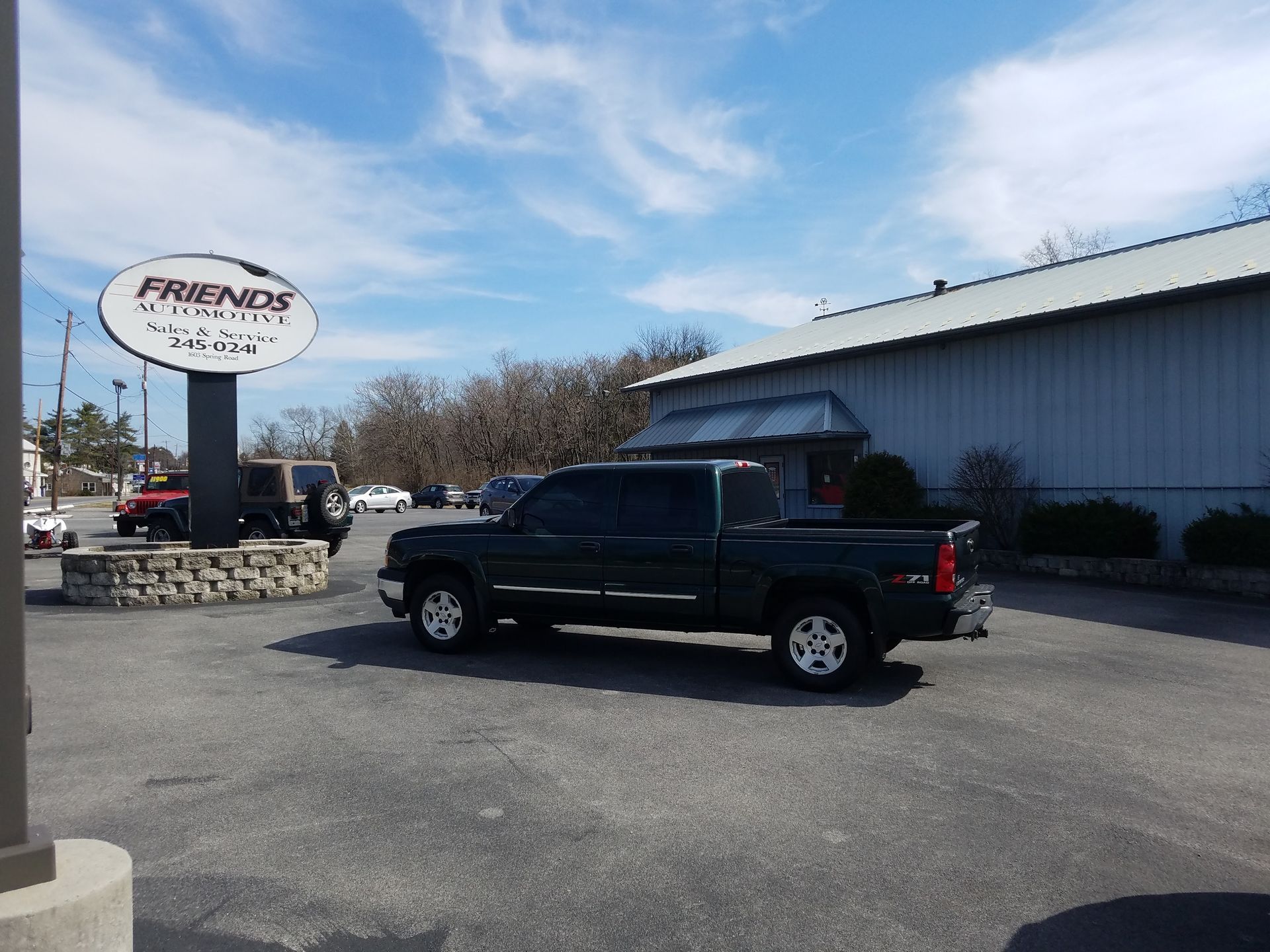 A green pickup truck parked in a lot in front of 