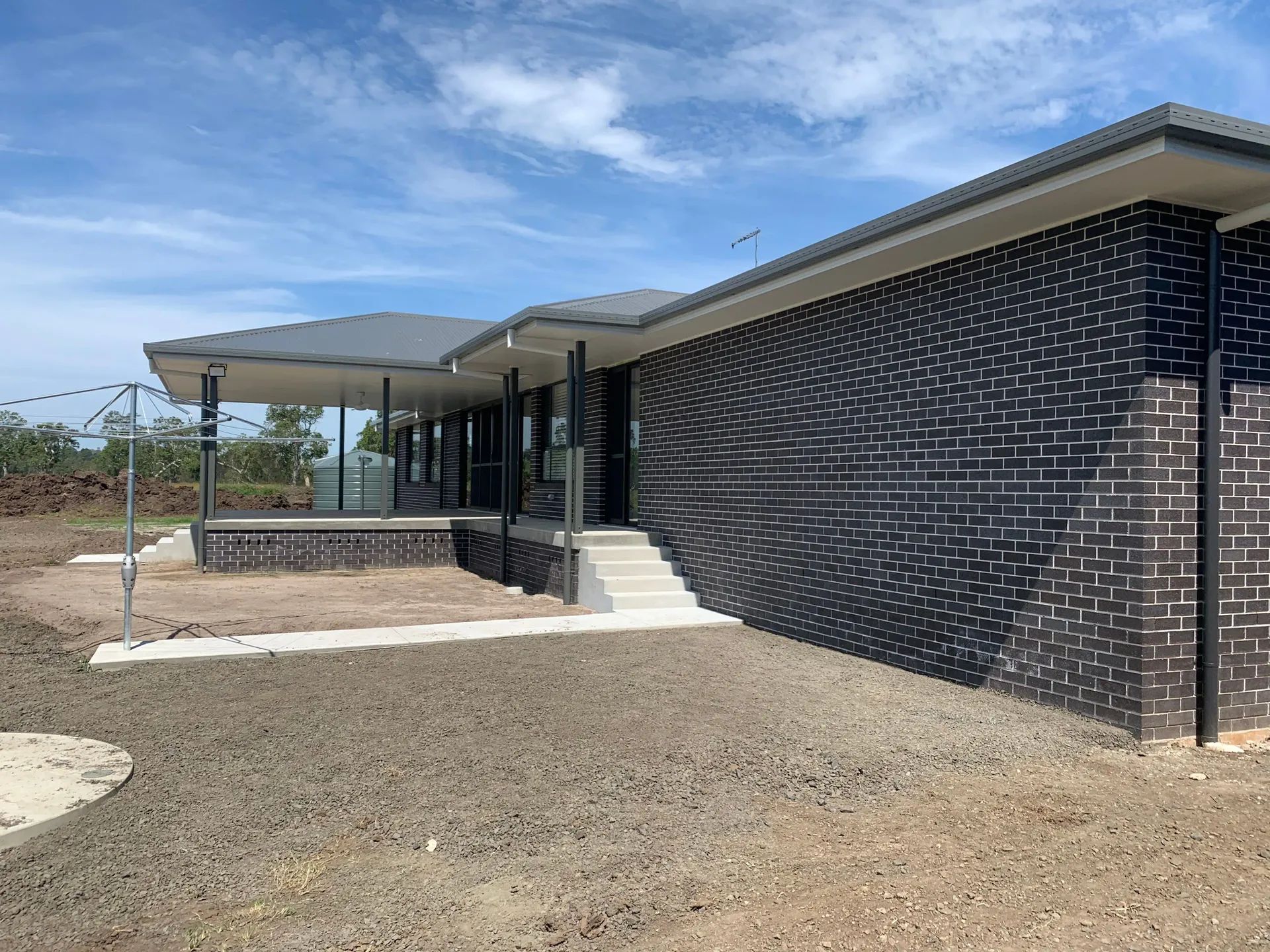 Modern, single-story house with dark brick exterior, porch, and a gray roof  — C & S Building Pty Ltd In Bentley, NSW