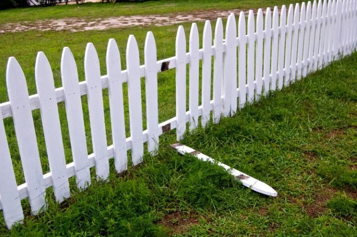 White picket fence with a broken section, lying on green grass.