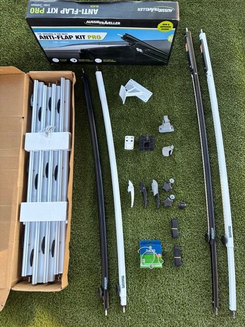 Anti-Flap Kit Pro laid out on artificial turf. Includes poles, clamps, box, and various hardware.