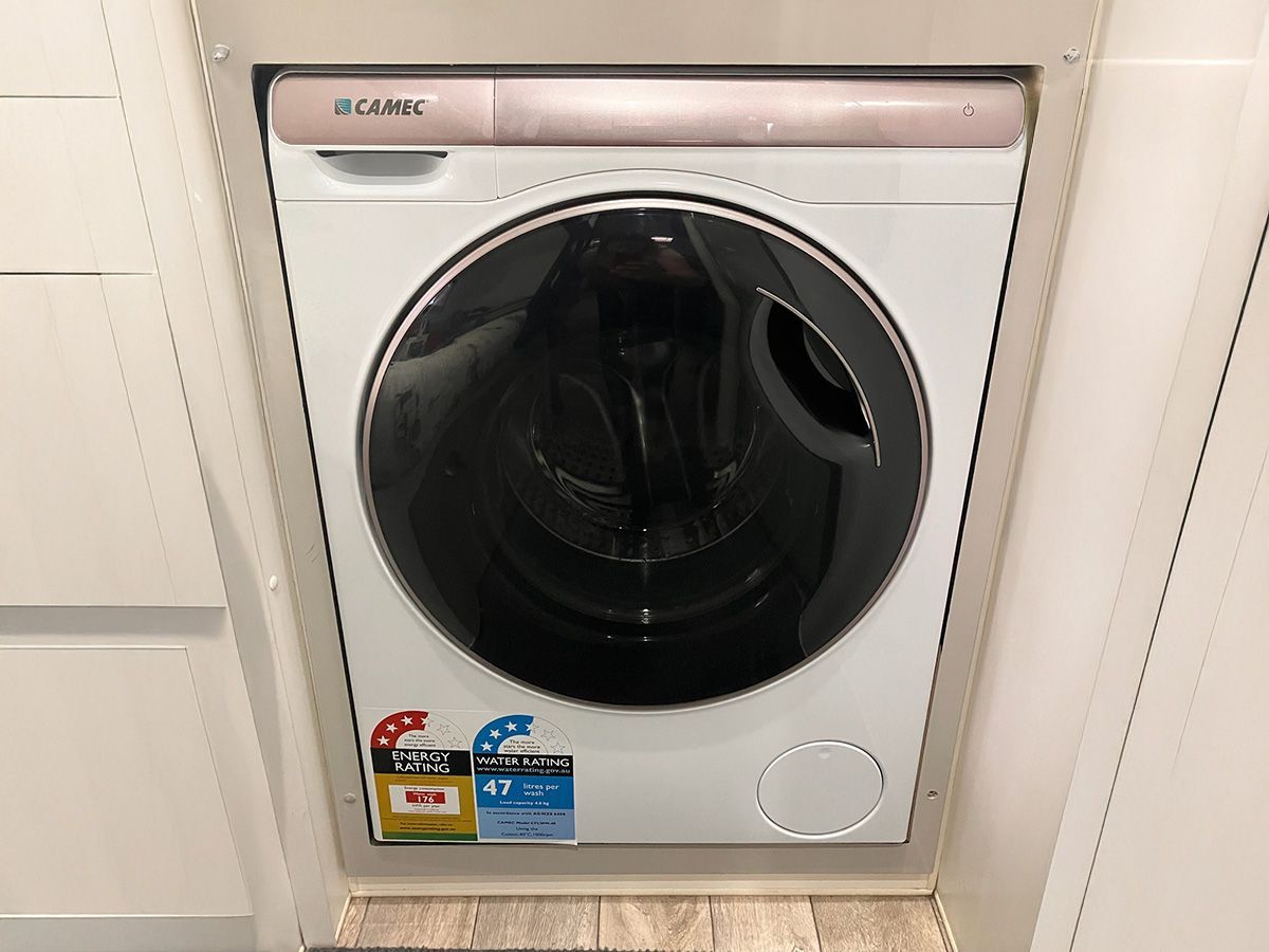 White washing machine built into a cabinet with energy efficiency sticker.