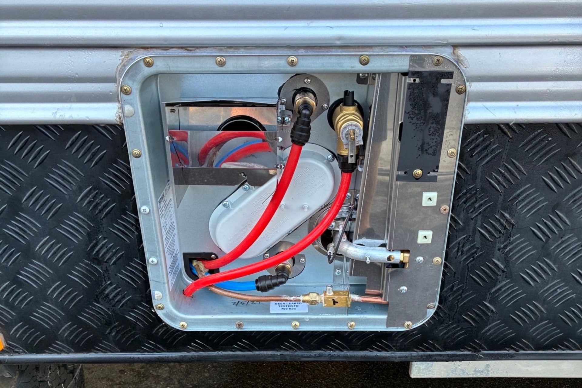 A camping trailer with its awning extended. It's parked on a grassy area, with trees in the background.