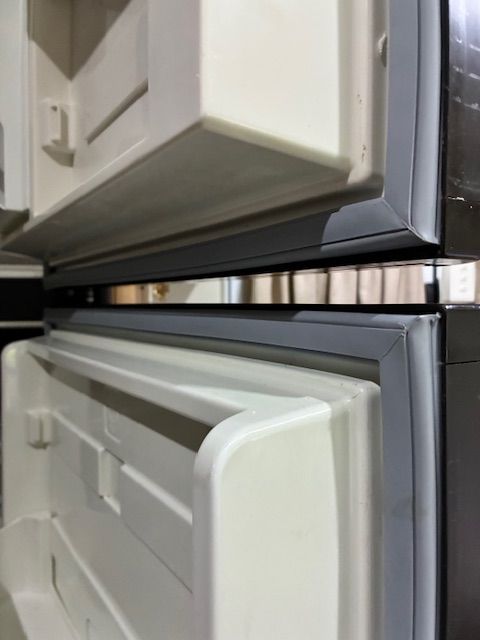 Open refrigerator doors, showing the interior, with white shelves and a dark grey seal.