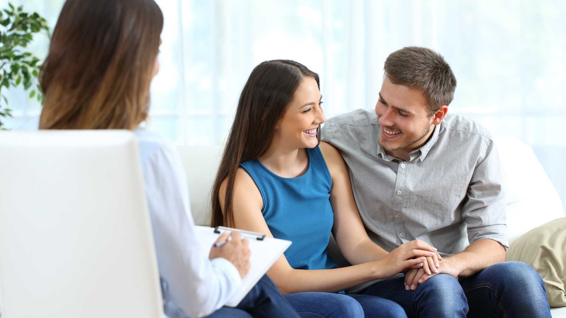A man and a woman are sitting on a couch talking to a woman.