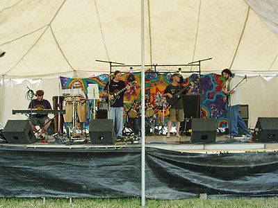 A group of people playing instruments on a stage under a tent
