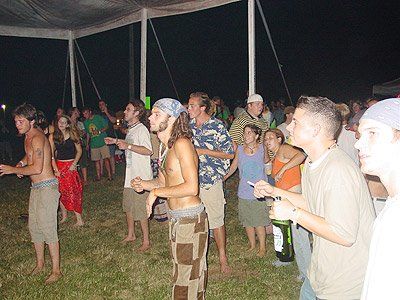 A group of people are dancing under a tent at night