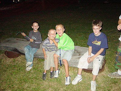 A group of young boys are sitting on a bench in the grass