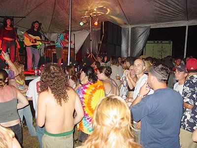 A group of people are dancing in front of a stage with a man playing a guitar