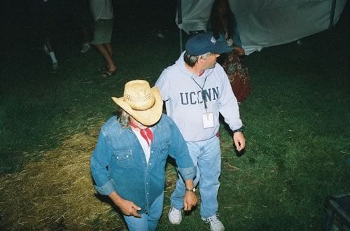 A man wearing a uconn sweatshirt is walking with another man. The man in the cowboy hat is Forrest Richard Betts. Dickey Betts!