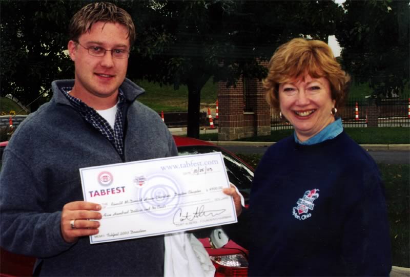 A man is holding a check that says Tabfest on it