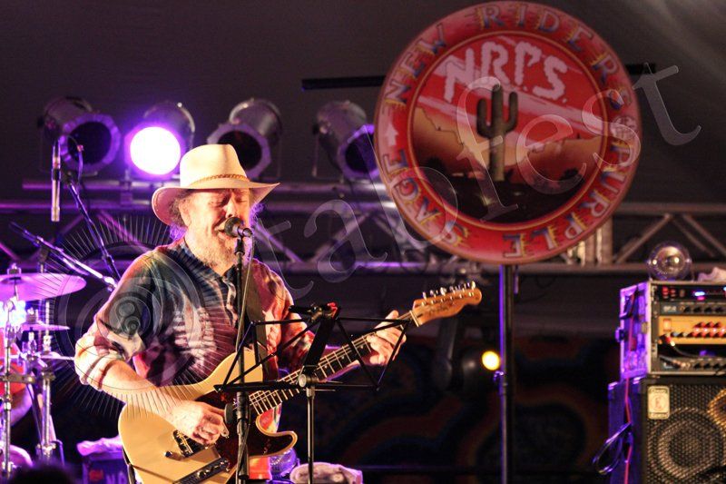 A man in a cowboy hat is singing into a microphone while playing a guitar