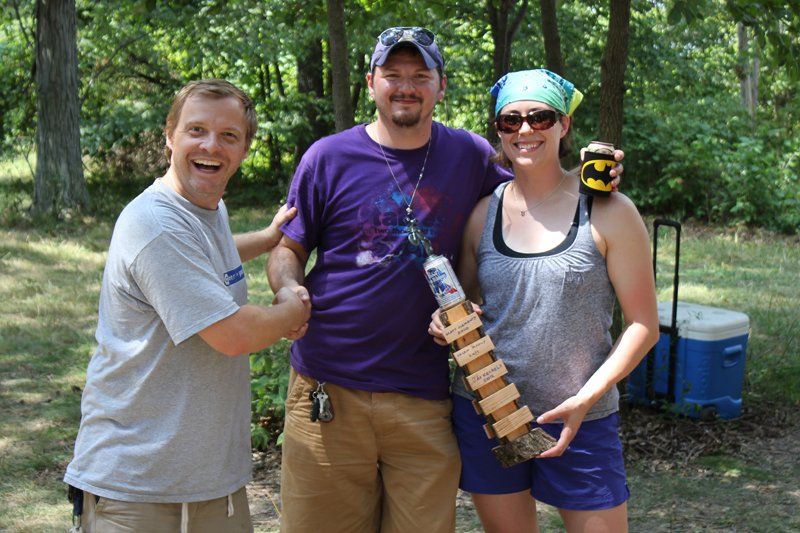 A man in a purple shirt is shaking hands with two other people