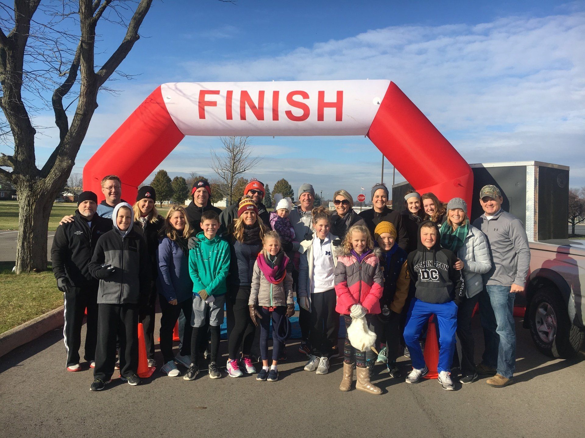 A group of people are posing for a picture in front of an inflatable finish line arch.
