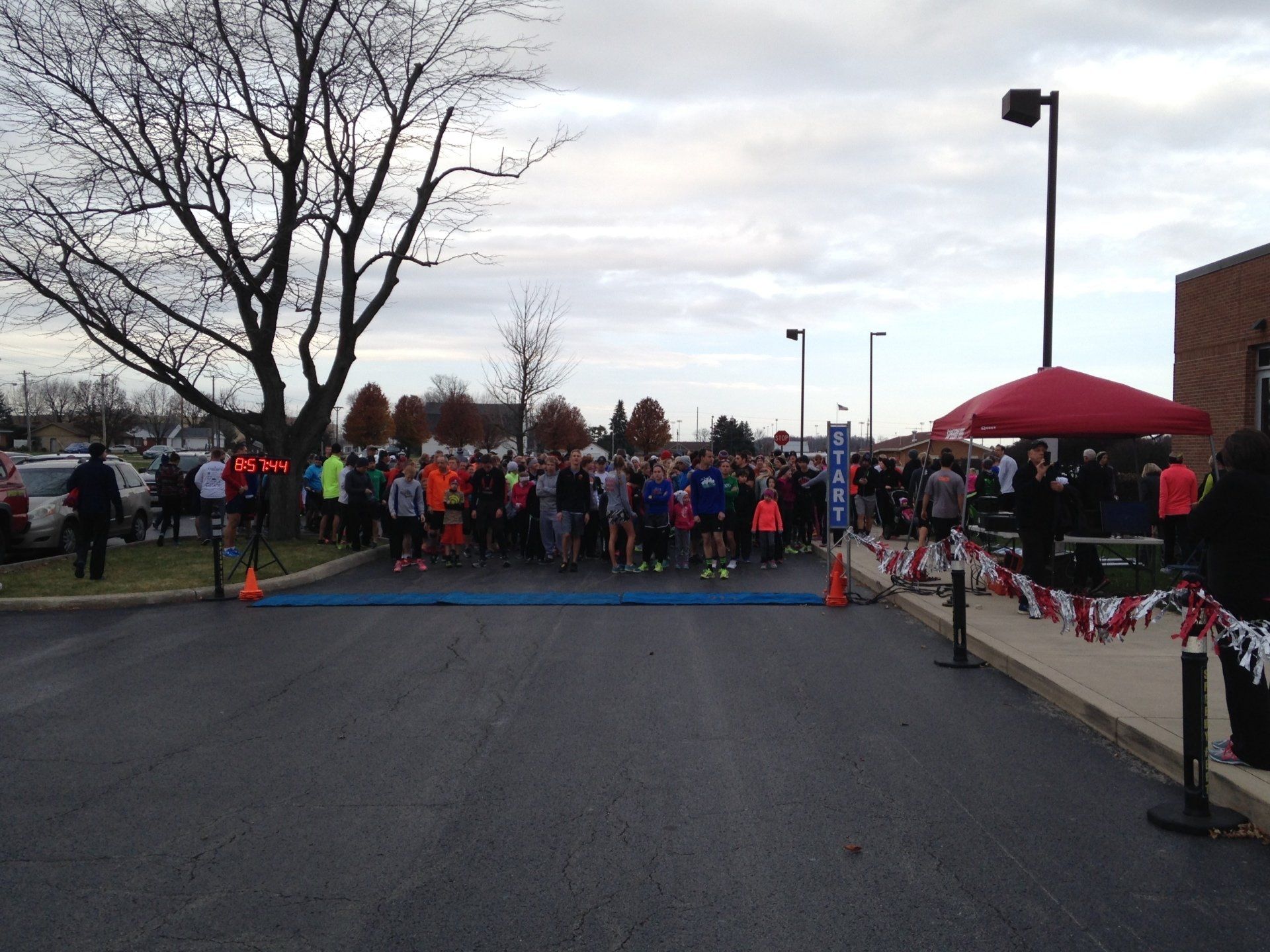 A large group of people are gathered in a parking lot for a race