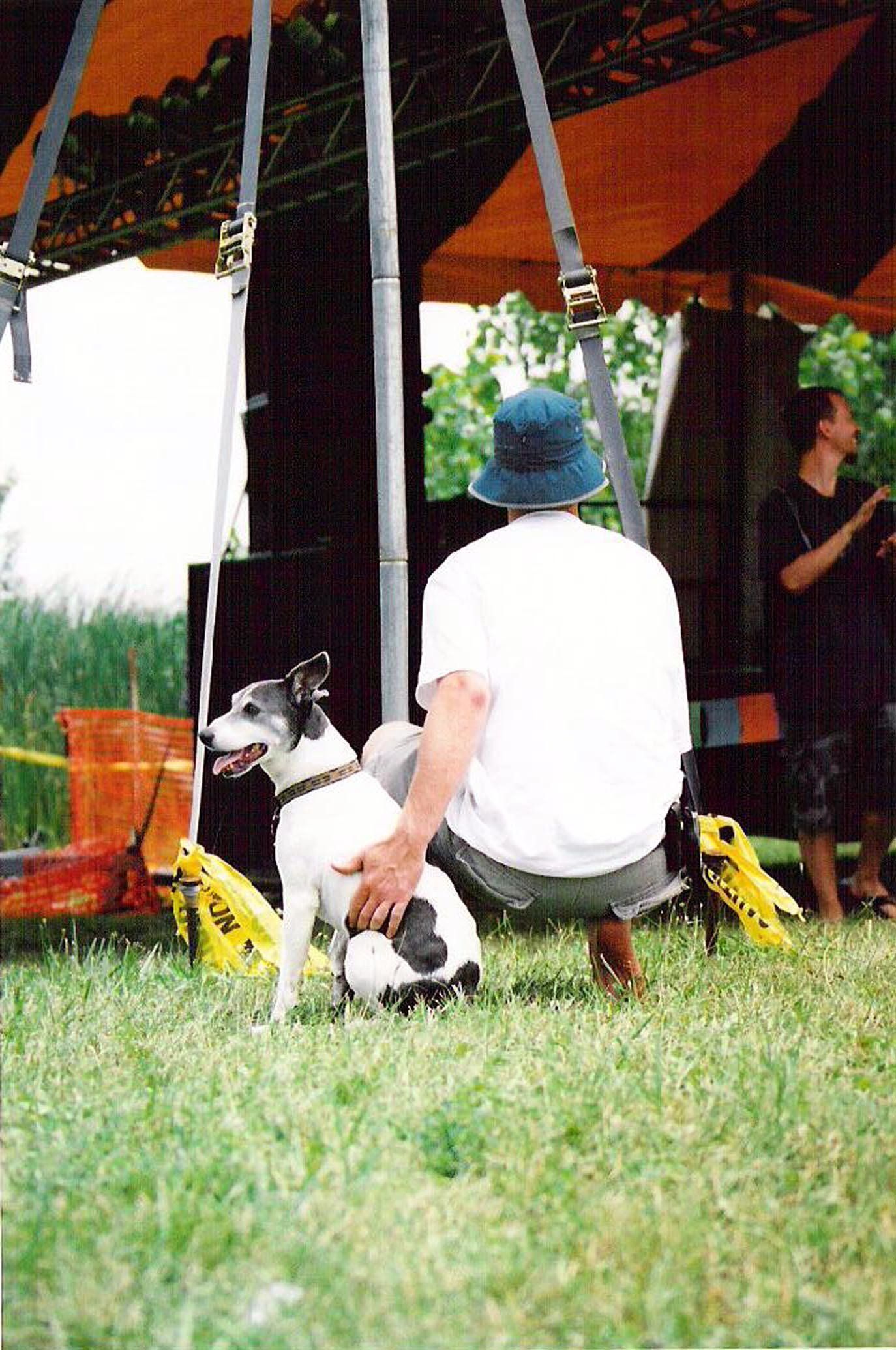 A man sits in the grass with his dog, Barkley, at Tabfest.