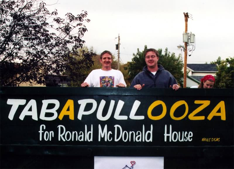 Two men holding a sign that says tabapullooza for ronald mcdonald house