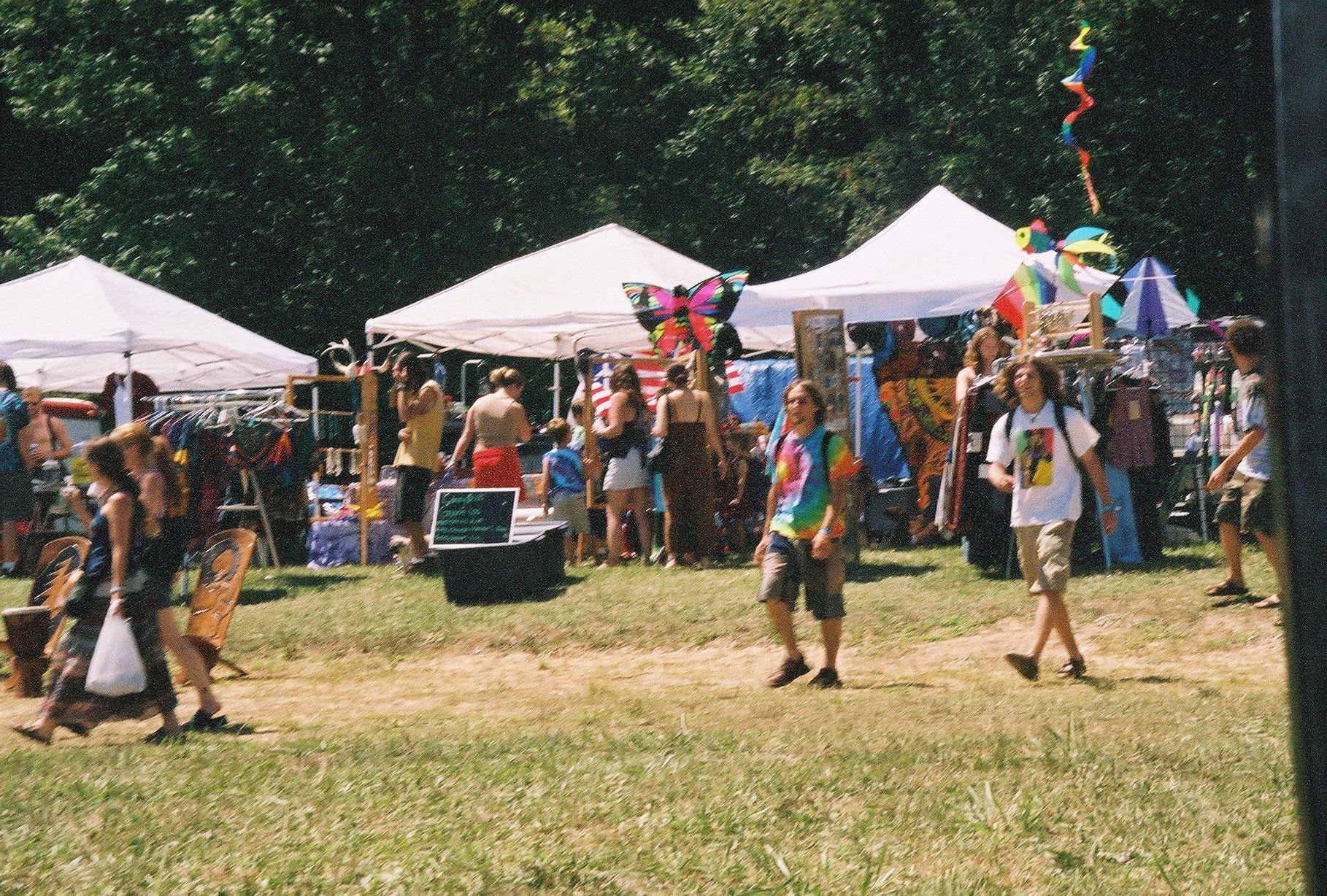 A group of people are walking in a field with tents.