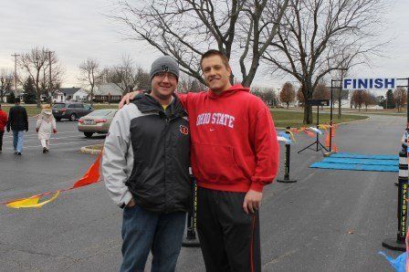 Two men are posing for a picture in front of a finish sign