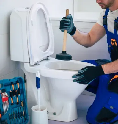 licensed plumber unclogging toilet with plunger.