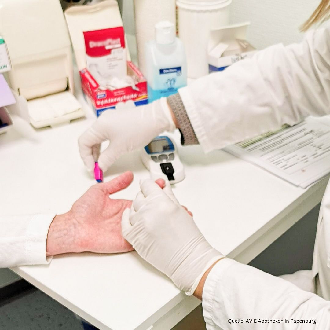 Eine Person mit Handschuhen bereitet die Hand des Kunden auf die Cholesterin-Messung am Finger vor