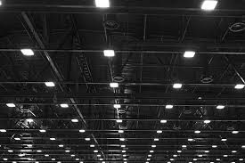 A black and white photo of the ceiling of a large building with lots of lights.
