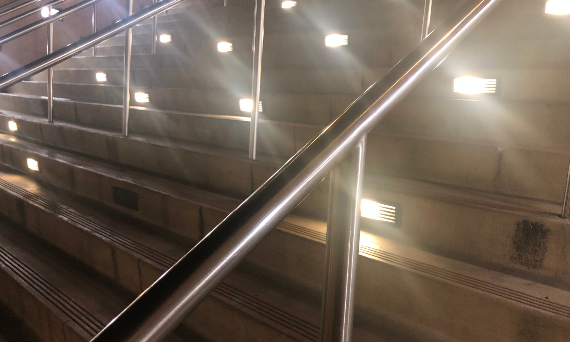 A staircase with a metal railing and lights on the steps