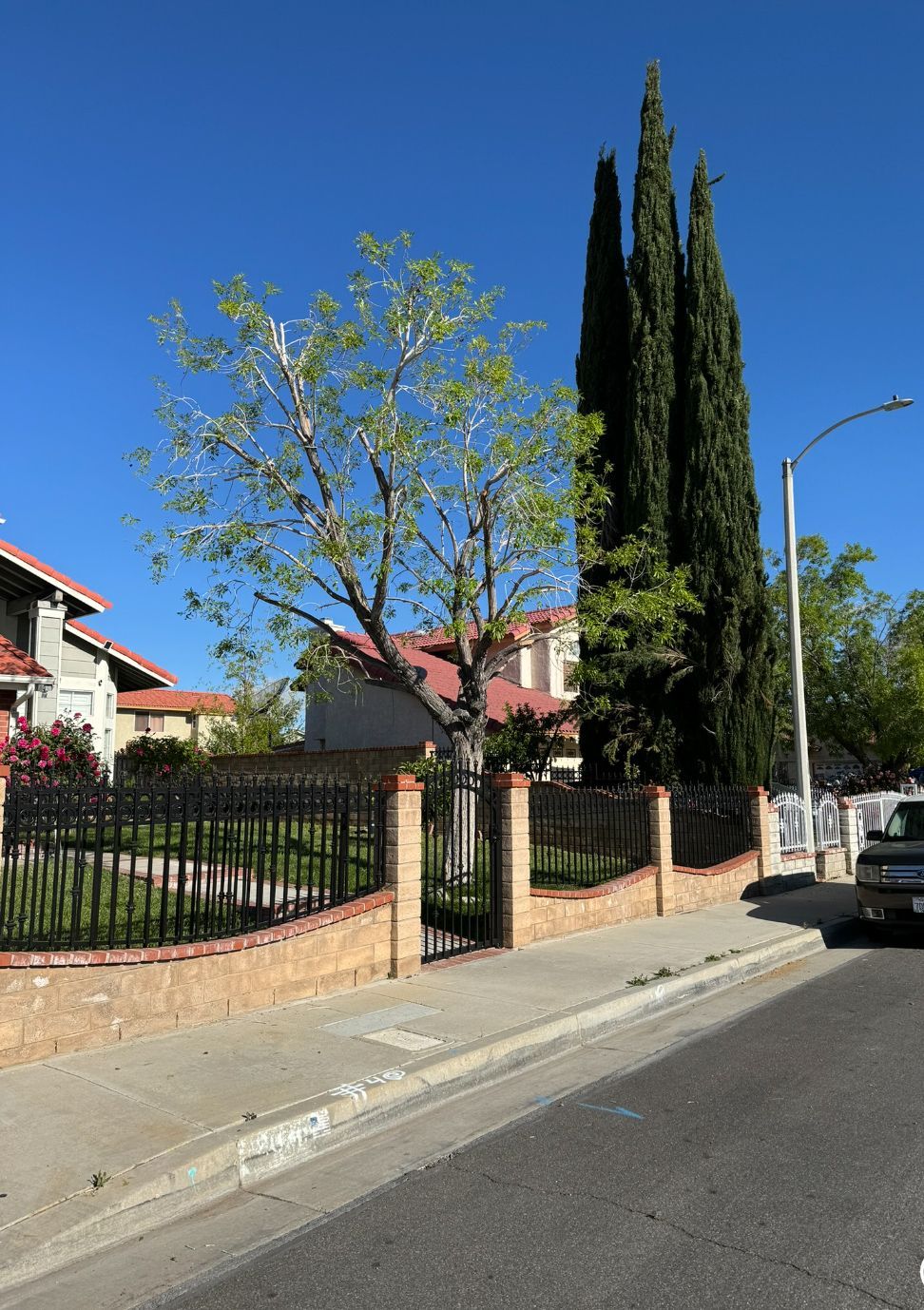 A car is parked on the side of the road next to a fence.