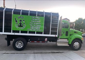 A green truck with the word ufo on the side is parked on the side of the road.