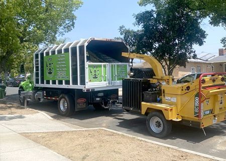 A truck with a chipper attached to it is parked on the side of the road.