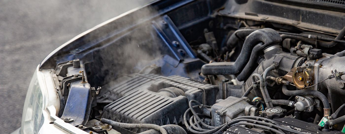 Steaming car engine, with visible components and rising vapor.