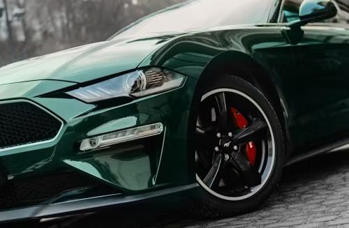 Green Ford Mustang with black wheels and red brake calipers.