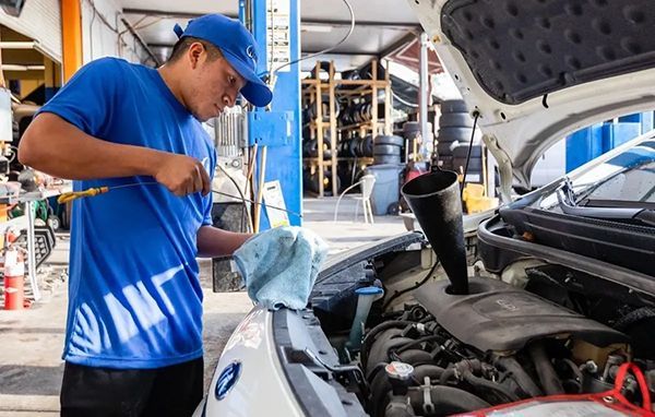A man is working on the engine of a car in a garage.