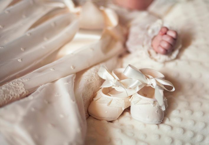 Un bambino indossa un vestito bianco e delle scarpe bianche.