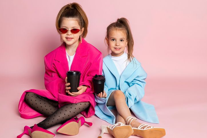 Due bambine sono sedute sul pavimento e tengono in mano delle tazze di caffè.