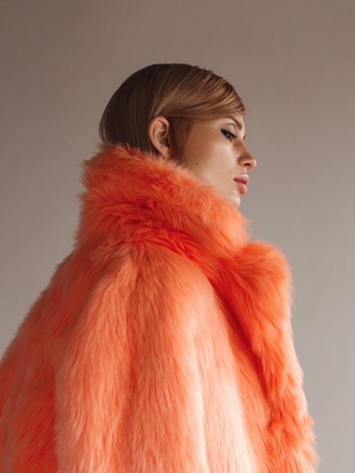 Una donna indossa una pelliccia arancione brillante.
